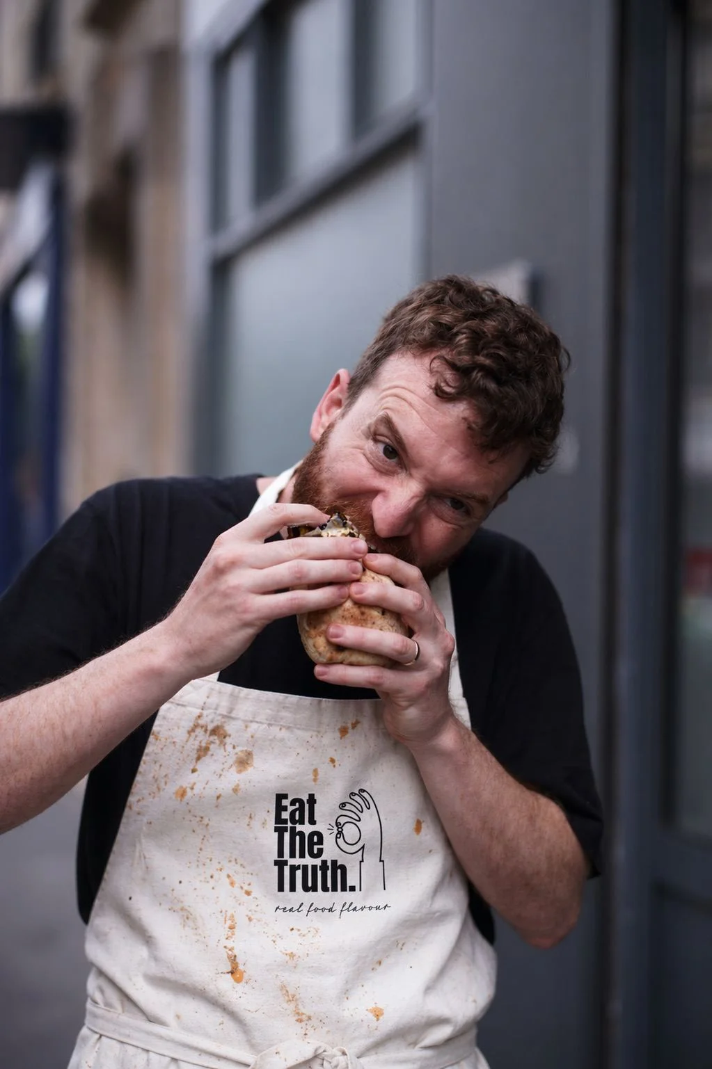 Chef in an Eat The Truth apron biting into food, expressing passion for real flavour
