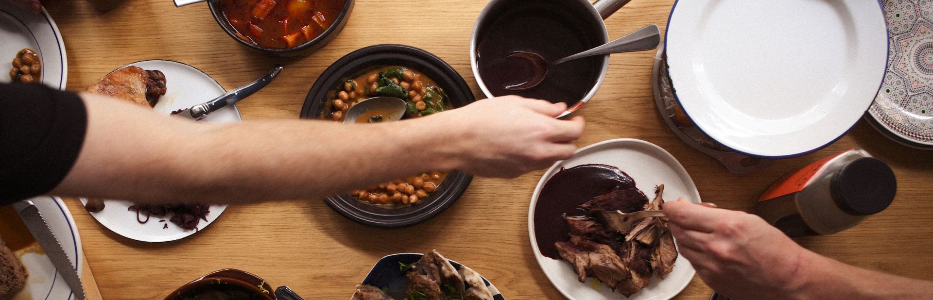 Overhead view of a shared table with plates of chickpeas, sauce and meat, banner for the EATTT blog