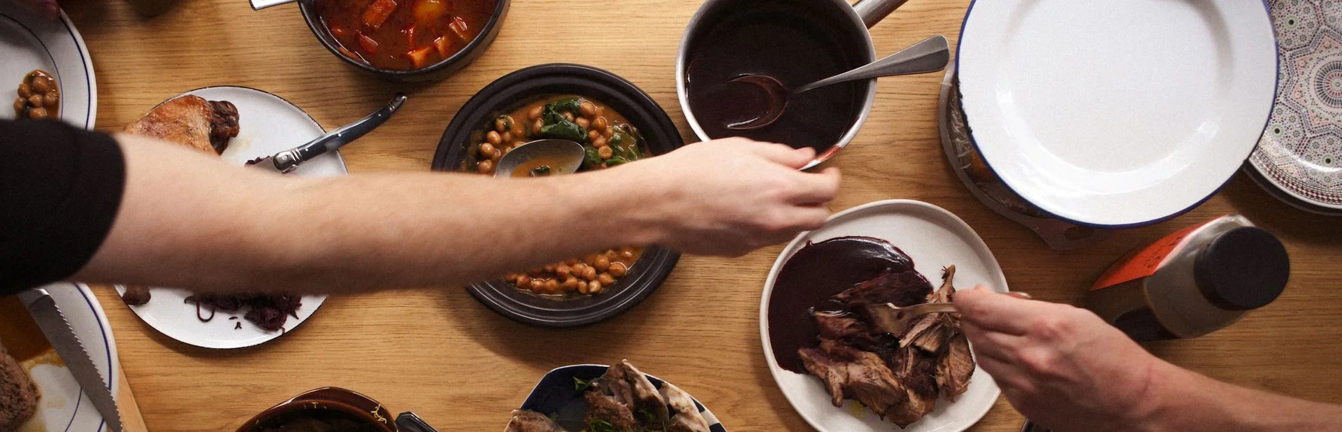 Vue de dessus d'une table partagée avec des assiettes de pois chiches, sauce et viande, bannière du blog EATTT