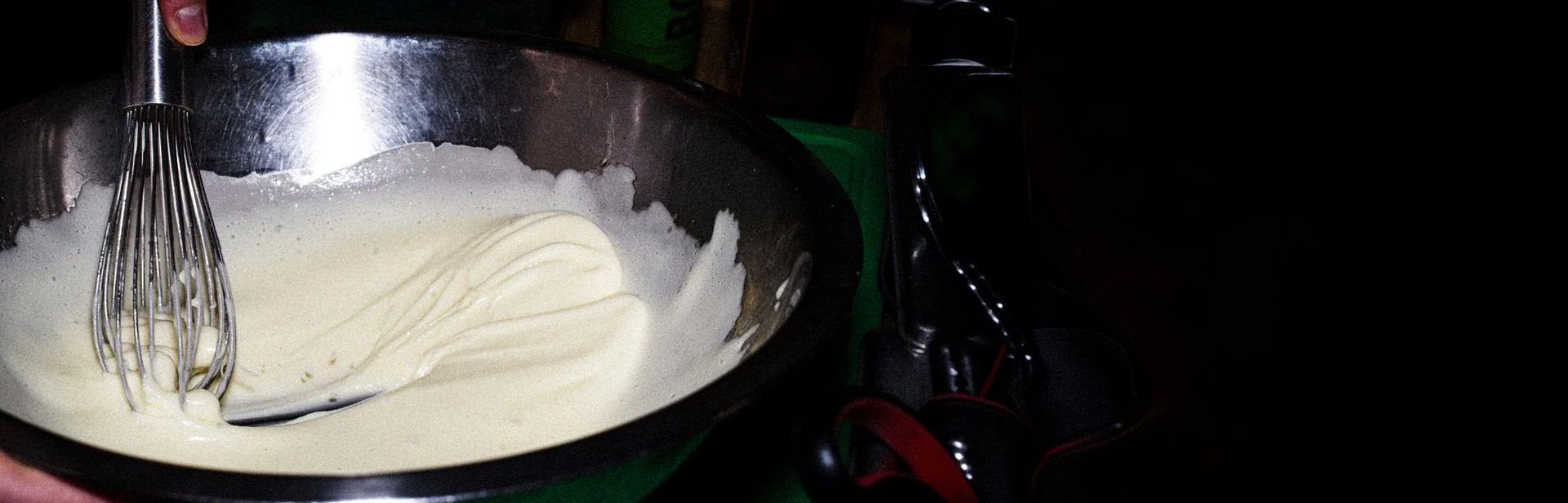 Fouet mélangeant une sauce blanche crémeuse dans un bol en métal avec une citation d'Alain Chapel