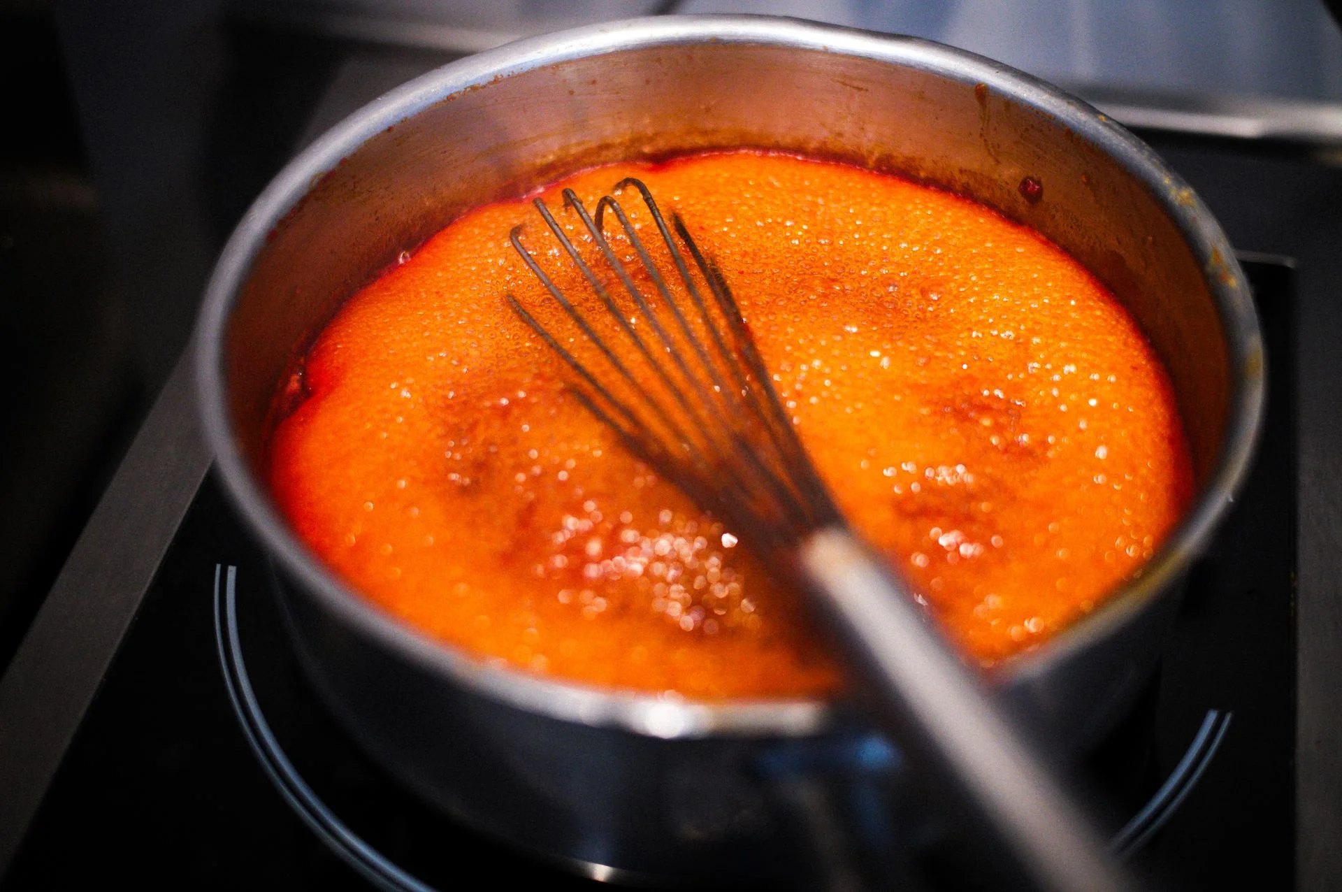 Close-up of a simmering sauce being whisked in a pot, banner for the Why We Cook page
