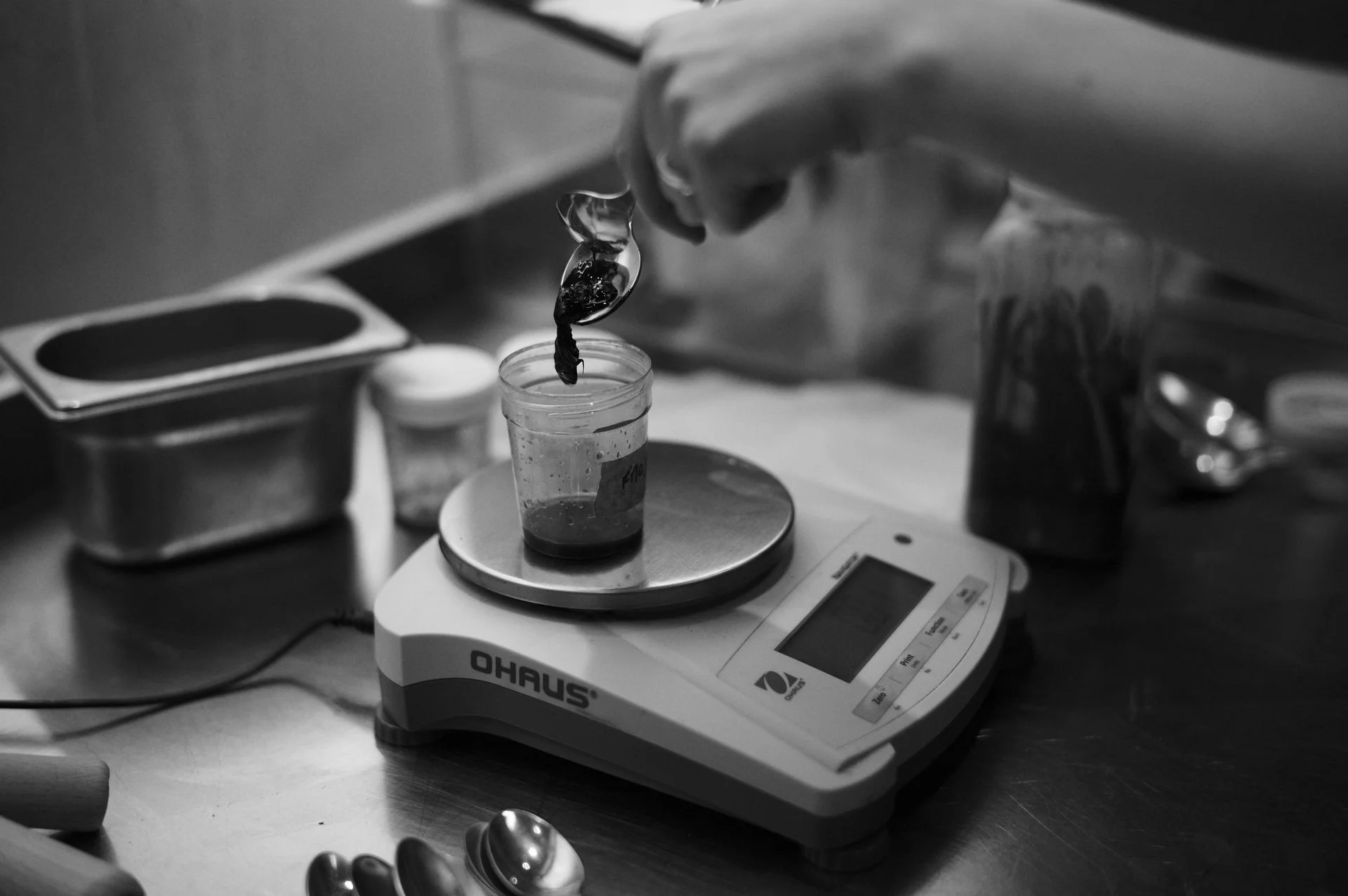 Black and white photo of a flavour sample being weighed on a lab scale, illustrating the black box problem in food transparency