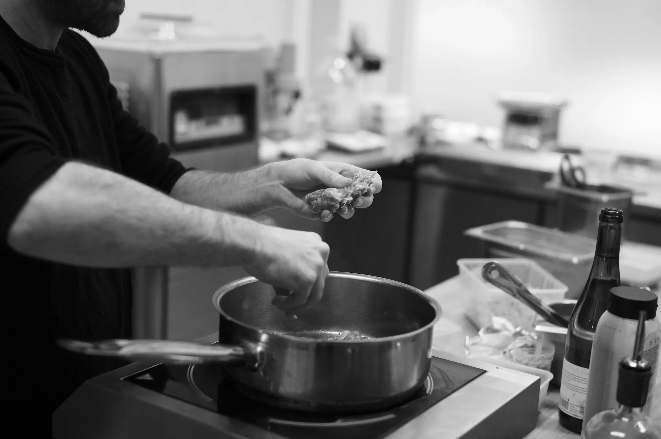 Chef ajoutant des ingrédients naturels dans une casserole pour créer de la profondeur aromatique à grande échelle.