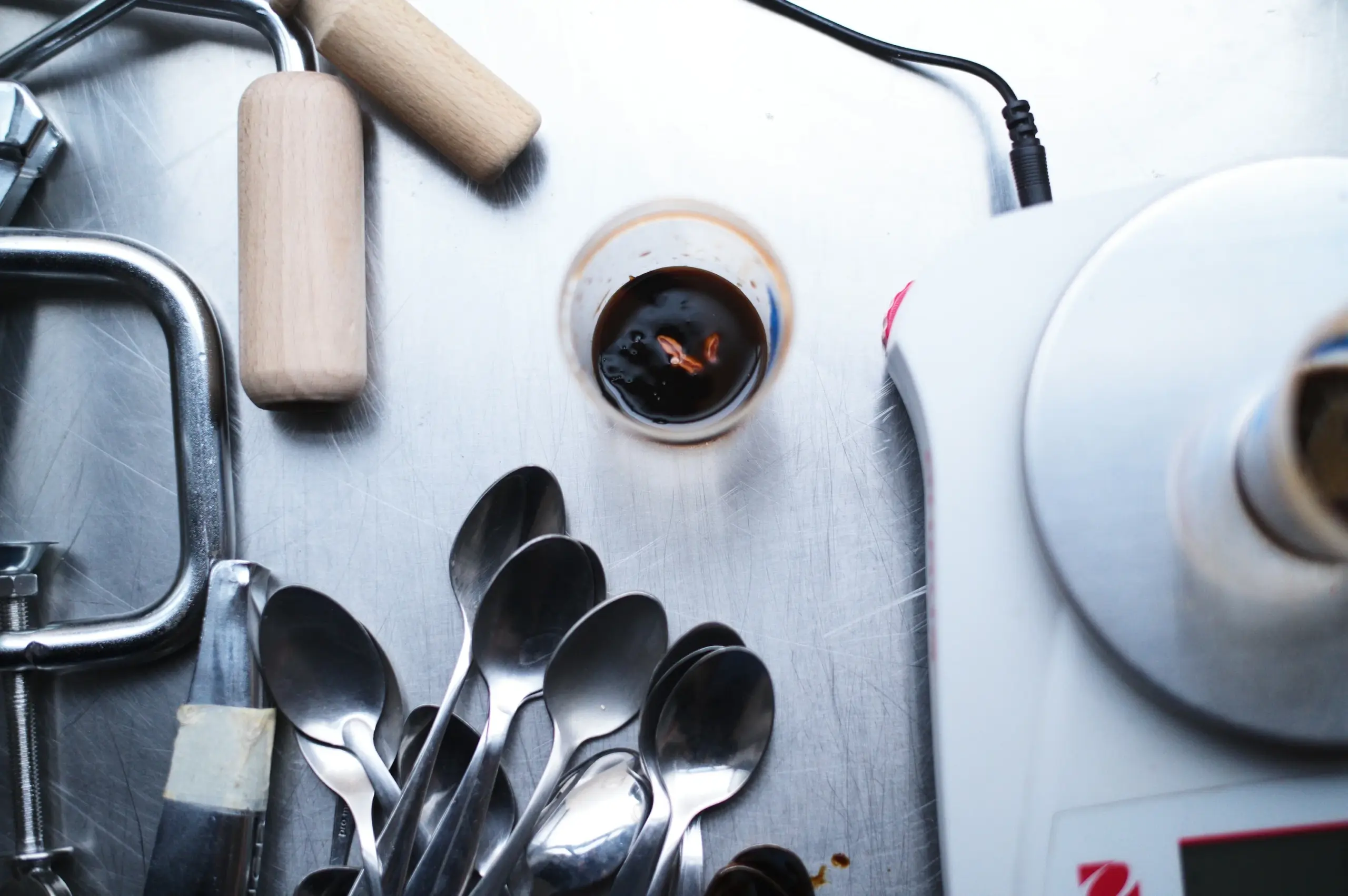 Vue à plat de cuillères de dégustation et d'une balance de laboratoire avec un échantillon de mélange fermenté.